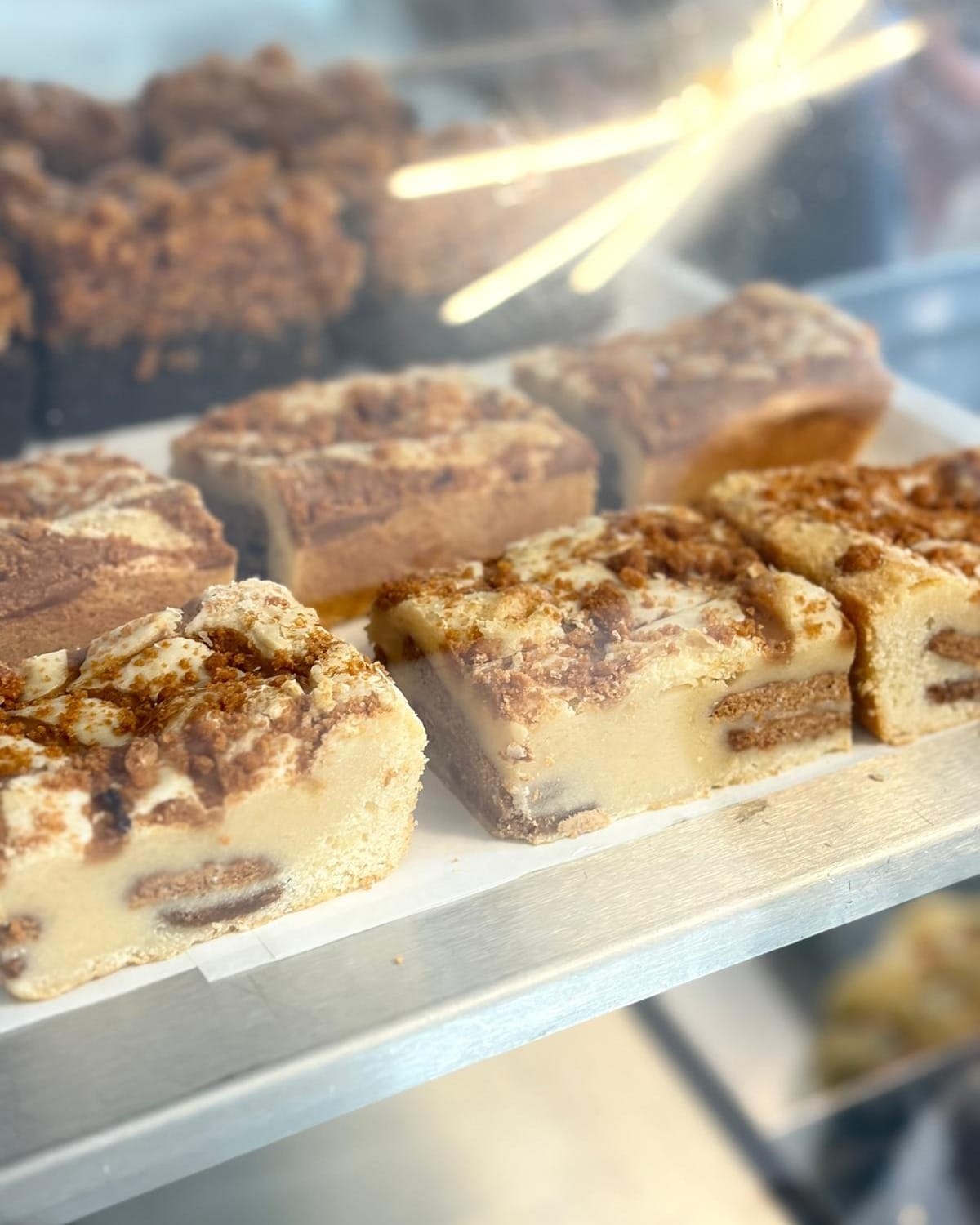 Trays of biscoff and custard traybakes on the counter, with brownies alongside